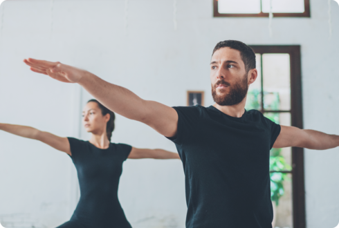 Koordinationsstörungen bei MS Ein Mann und eine Frau üben eine Yoga-Figur aus.