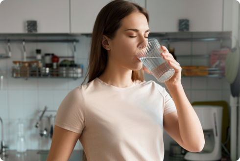 Eine Frau trinkt ein Glas Wasser. 