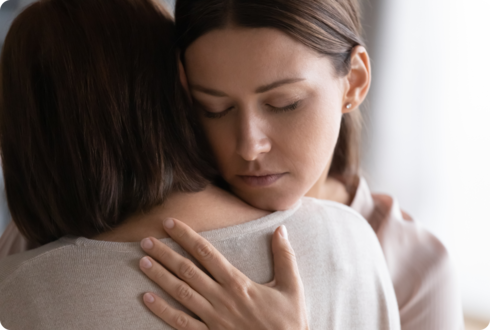 Ein Mädchen umarmt eine Frau und schließt dabei die Augen. 