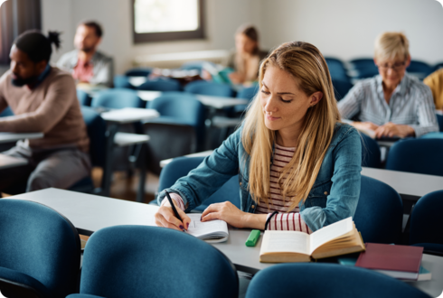 Tipps für Studium und Beruf Eine junge Frau sitzt in einem Raum und schreibt in ein Arbeitsheft.