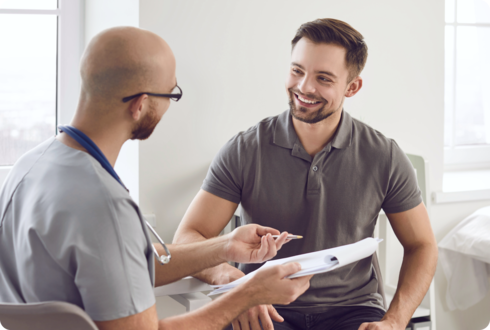 Ein junger Mann und ein Arzt sitzen sich gegenüber.