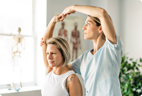 Eine Ärztin hält den Arm einer Frau in einer nach oben gestreckten Position.