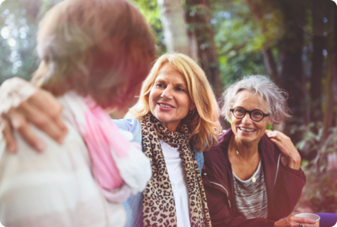 Eine Frau legt ihre Arme um zwei weitere Frauen.
