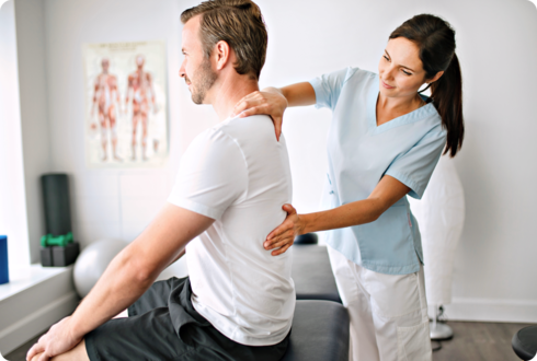 Eine Ärztin tastet den Rücken eines Mannes ab.