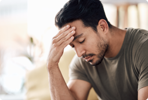 Fatigue bei MS Ein Mann hält sich die Schläfe und sieht erschöpft aus.