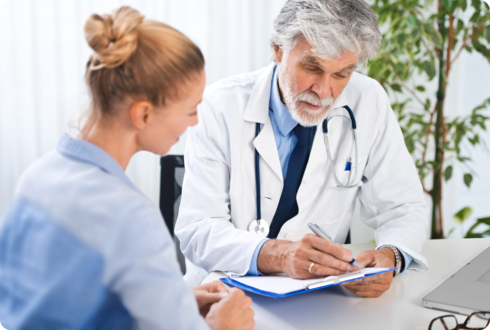 Frühzeitiger Therapiestart Ein Arzt und eine junge Frau schauen auf ein Klemmbrett.
