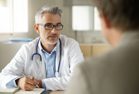 Ein Arzt und ein Mann sitzen sich gegenüber. 