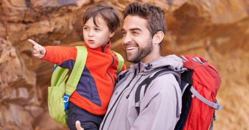 Ein Mann hält ein Kind auf dem Arm, beide lachen.