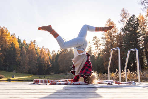 Eine Frau beim Yoga-Kopfstand im Sonnenaufgang.