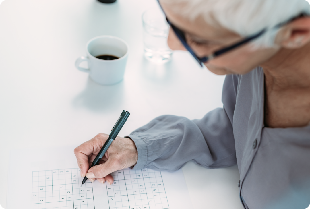 Eine ältere Frau arbeitet an einem Sudoku. 