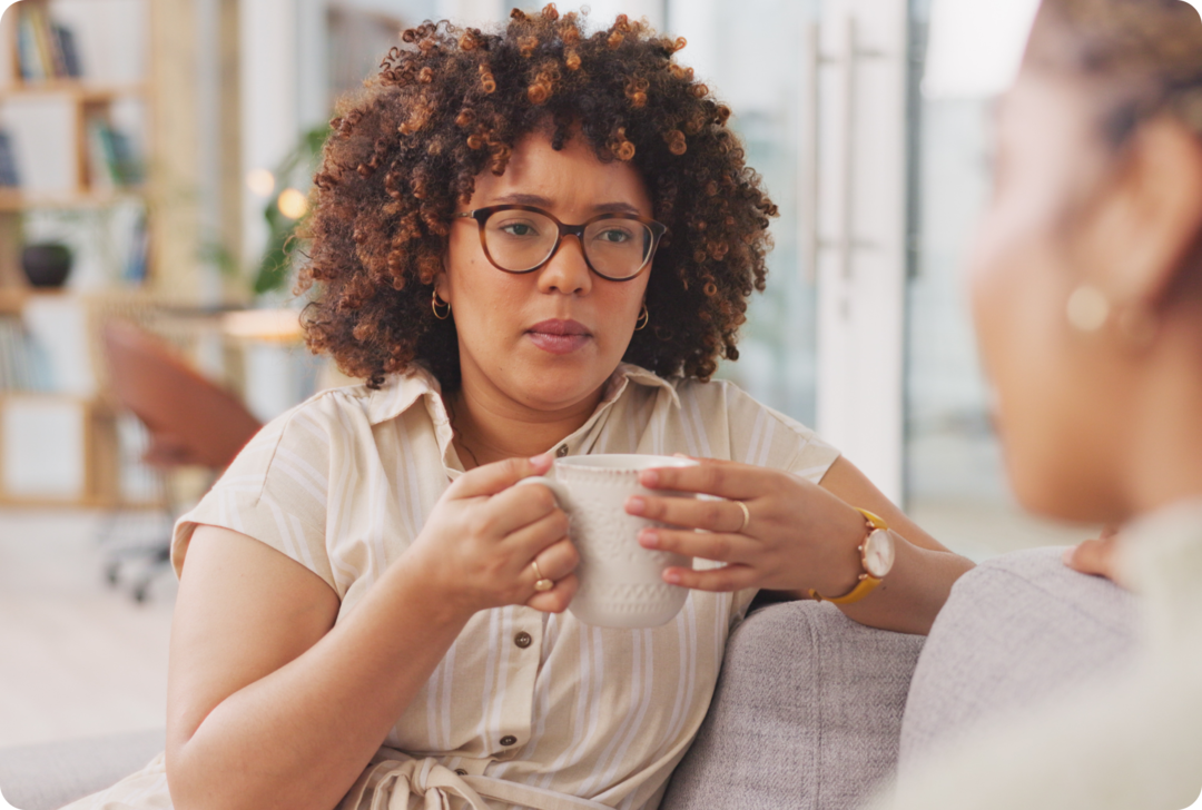 Zwei Frauen sitzen auf einem Sofa und schauen sich an.