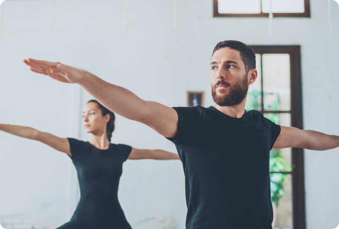 Koordinationsstörungen bei MS Ein Mann und eine Frau üben eine Yoga-Figur aus.