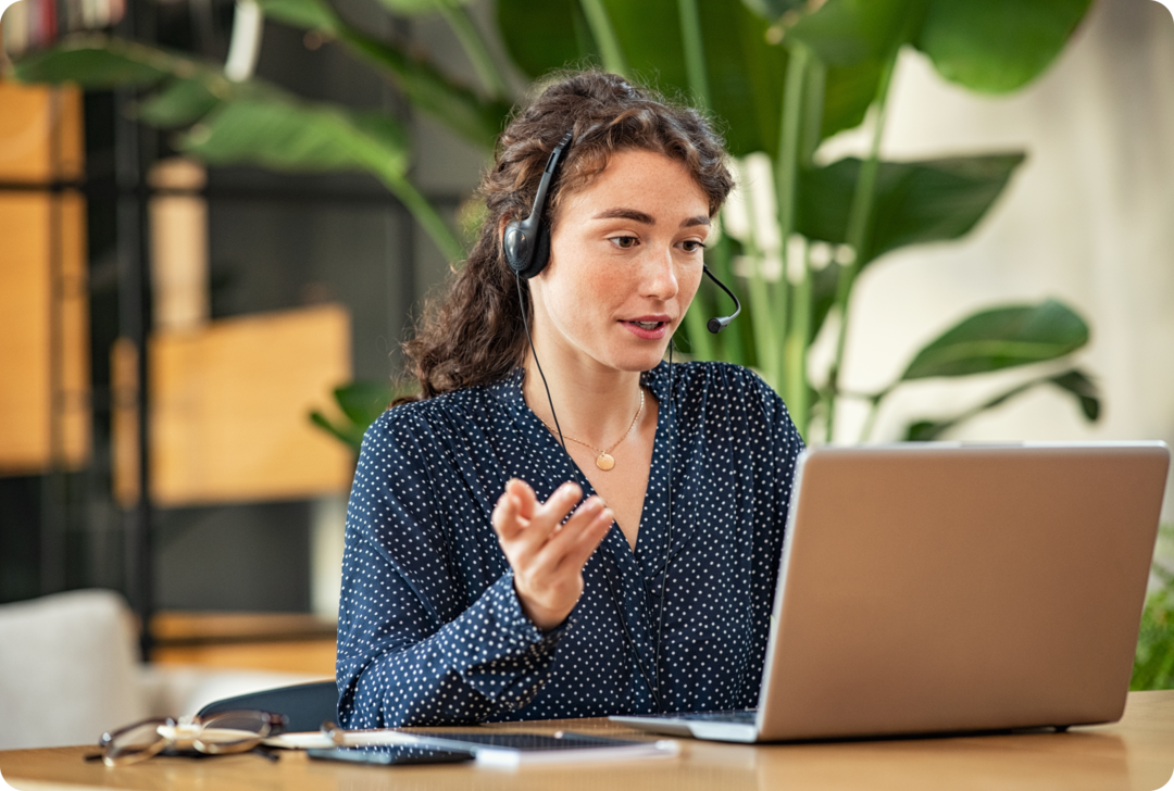 MS: Arbeit Eine Frau mit Headset schaut in ein Notebook und gestikuliert.