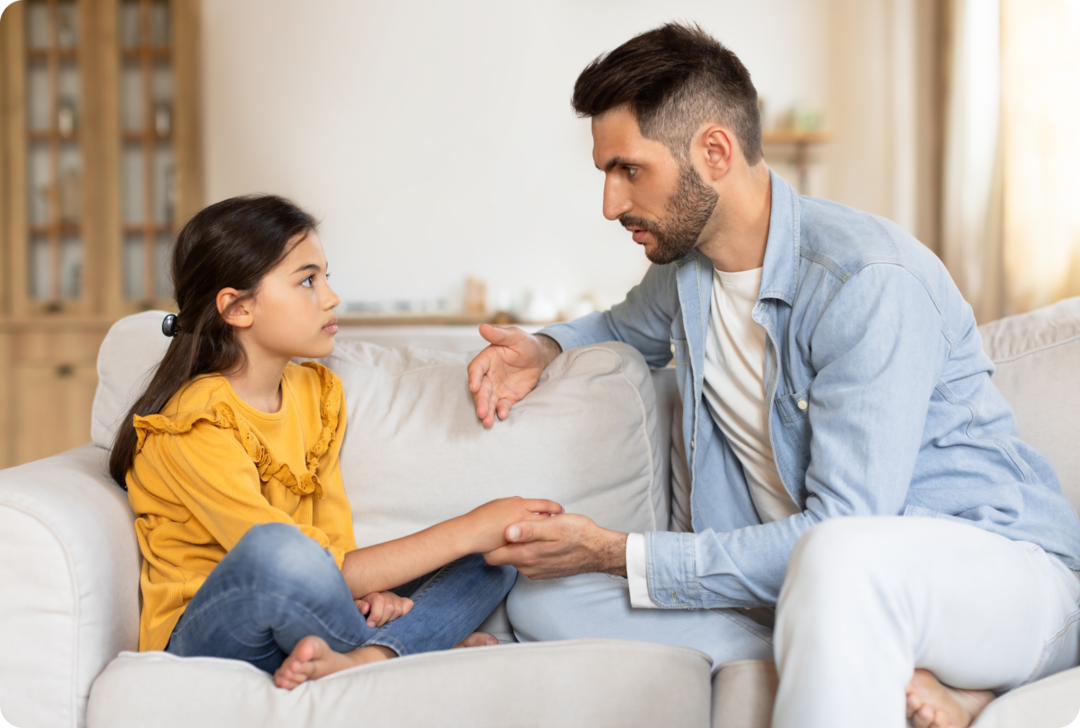Ein Mann und ein junges Mädchen sitzen auf einem Sofa und schauen sich an. 