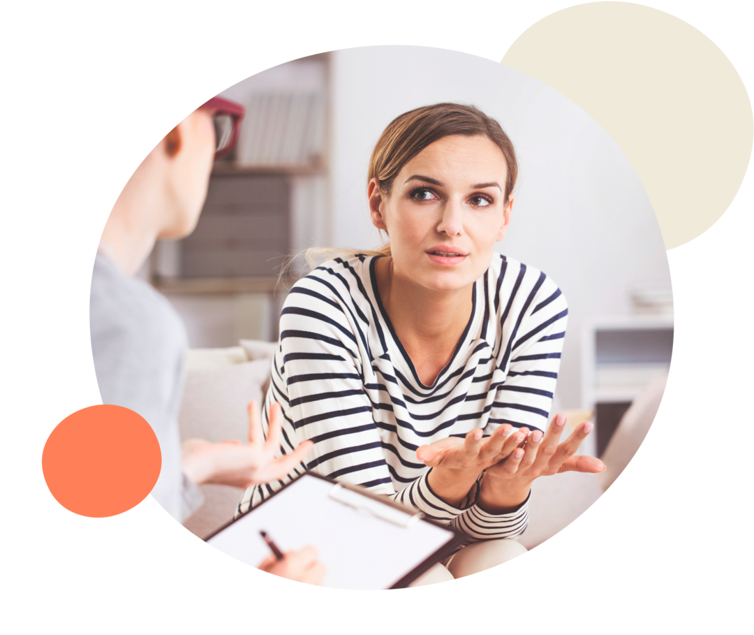 Zwei Frauen auf einem Sofa unterhalten sich und gestikulieren mit den Händen.