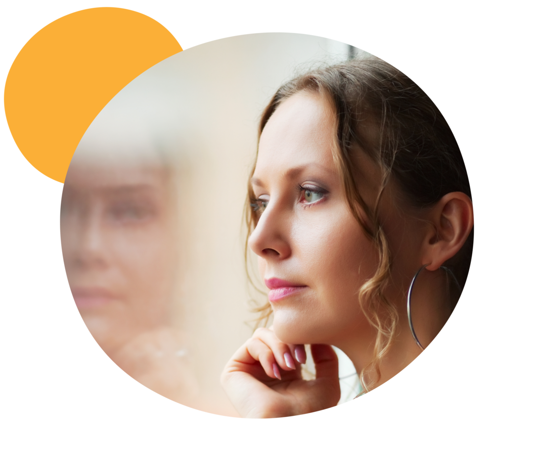 Eine Frau schaut nachdenklich aus dem Fenster. 