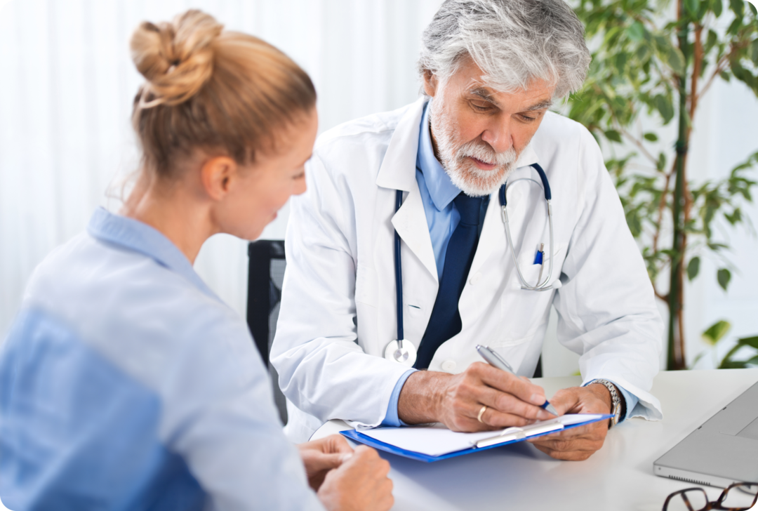 Frühzeitiger Therapiestart Ein Arzt und eine junge Frau schauen auf ein Klemmbrett.