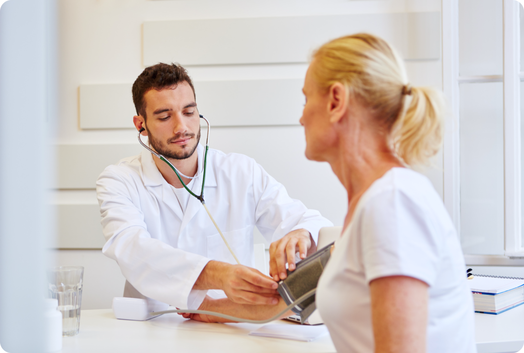 Ein Mann misst den Blutdruck einer Frau.