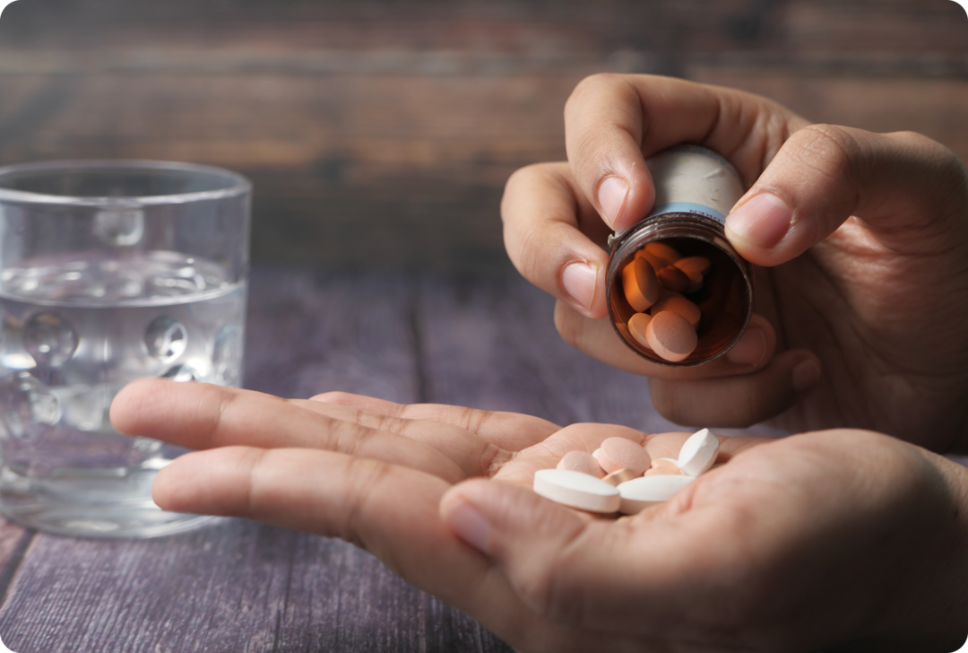 MS: Therapietreue Eine Frau schüttet sich aus einer Dose Tabletten in die Hand.