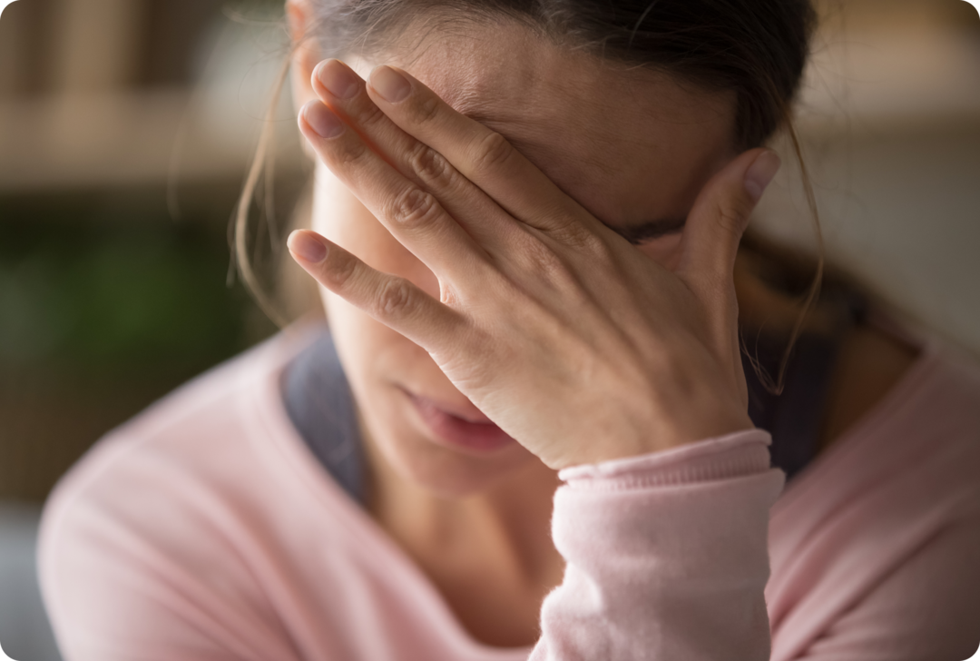 MS. Sehstörungen Eine Frau hat den Kopf gesenkt und hält sich die linke Hand vor die Augen.
