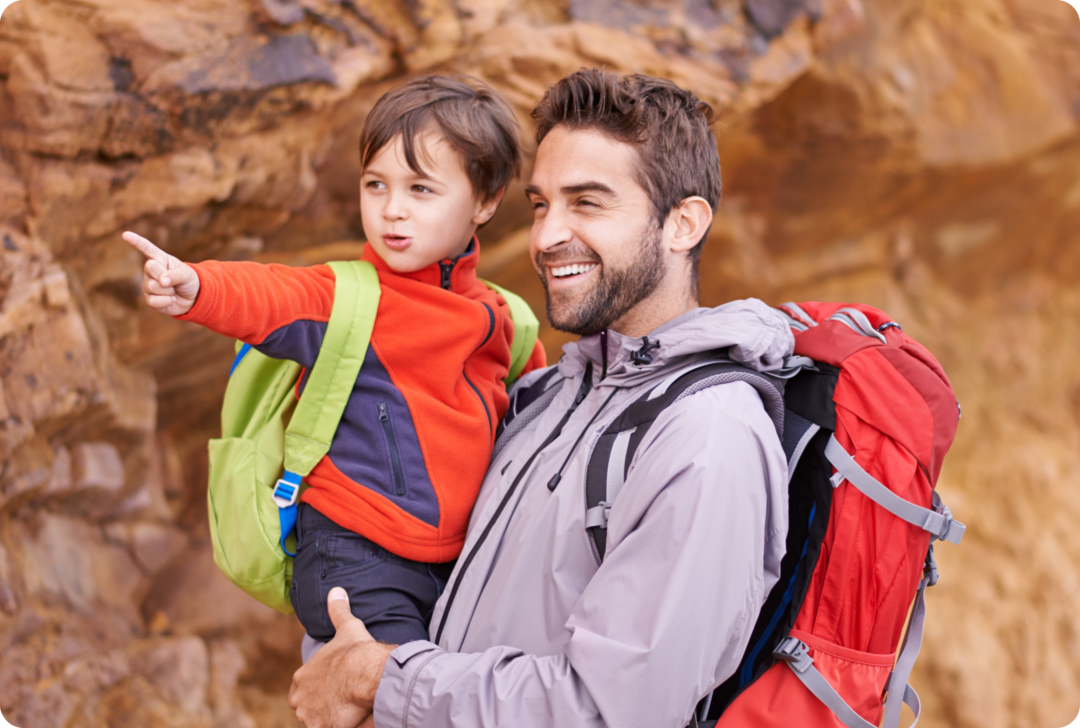 Ein Mann hält ein Kind auf dem Arm, beide lachen.